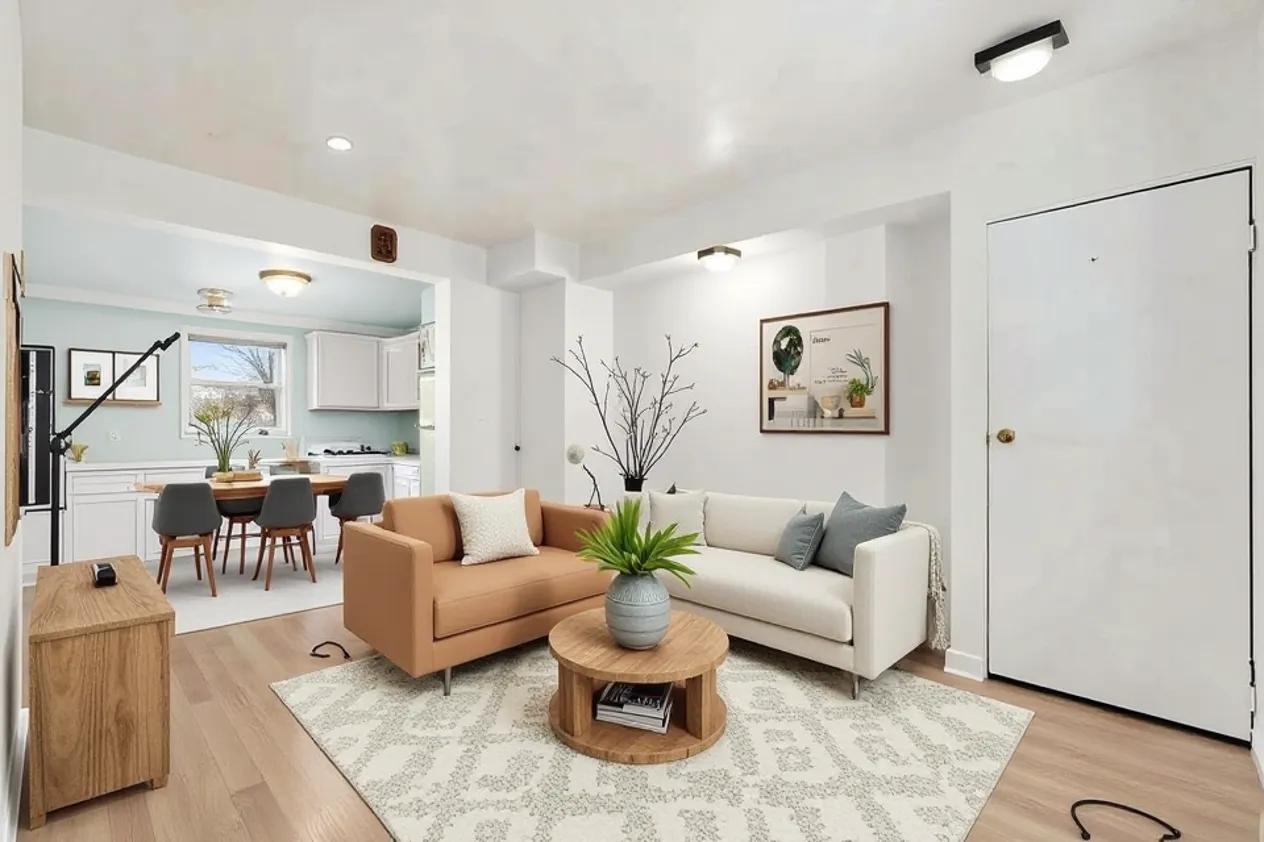 Living room opening into the kitchen, with light wood floors and a window over the sink